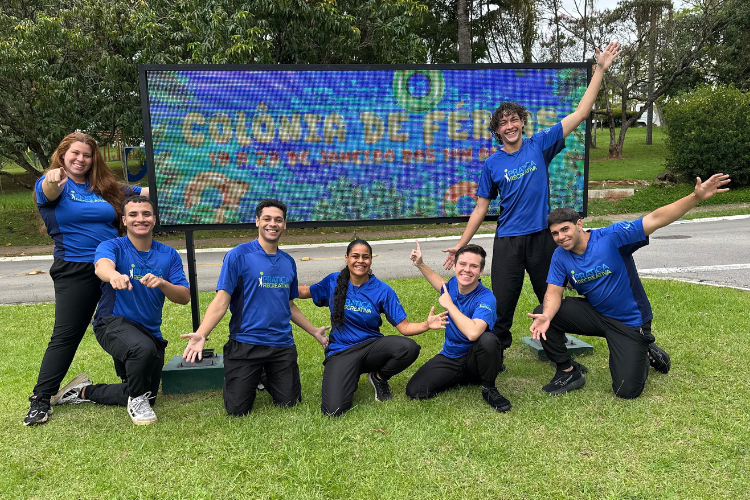 Crianças e recreadores comemorando juntos durante um dia de colônia de férias em condomínio