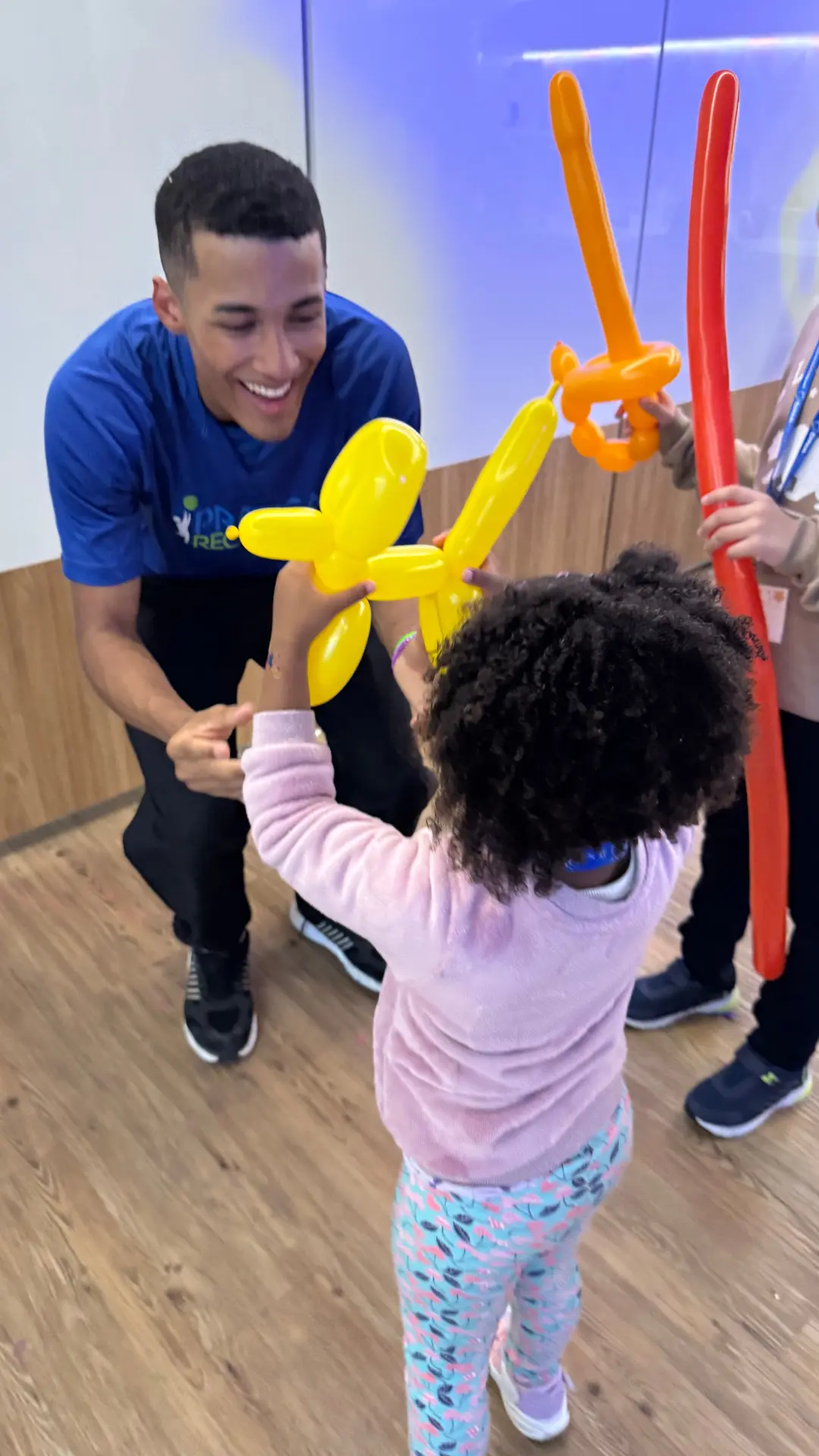 Recreador da Prática Recreativa entregando balão moldado a uma criança em Kids Day