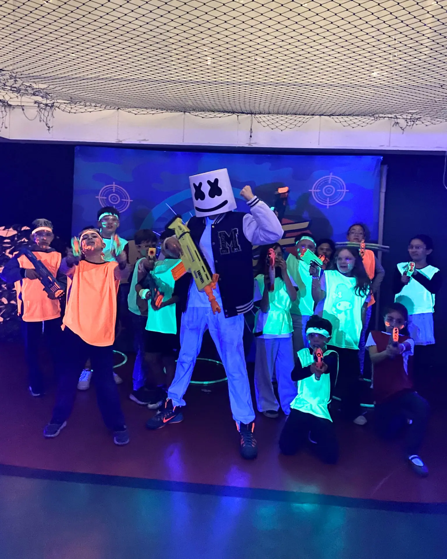 Turma posando com personagem caracterizado depois da batalha Nerf em salão de festas