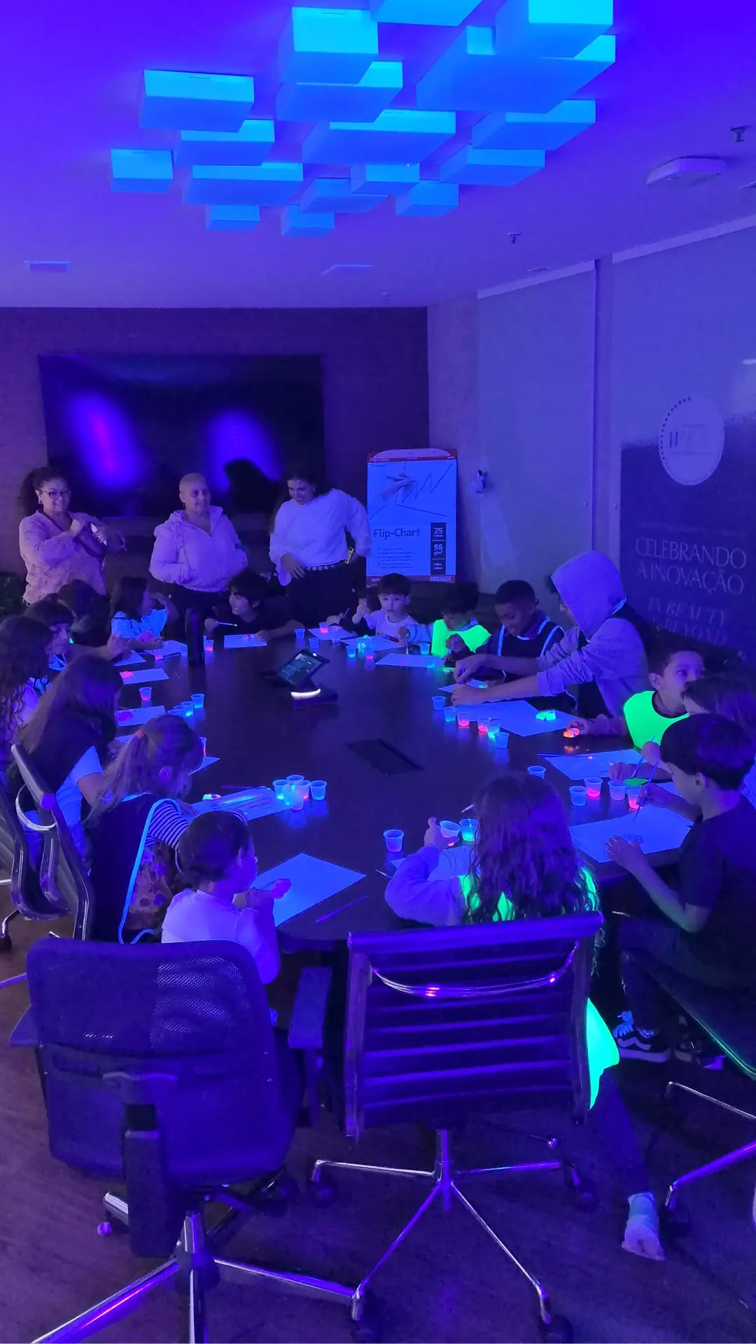 Crianças em oficina criativa com tinta neon na sala de reuniões da empresa