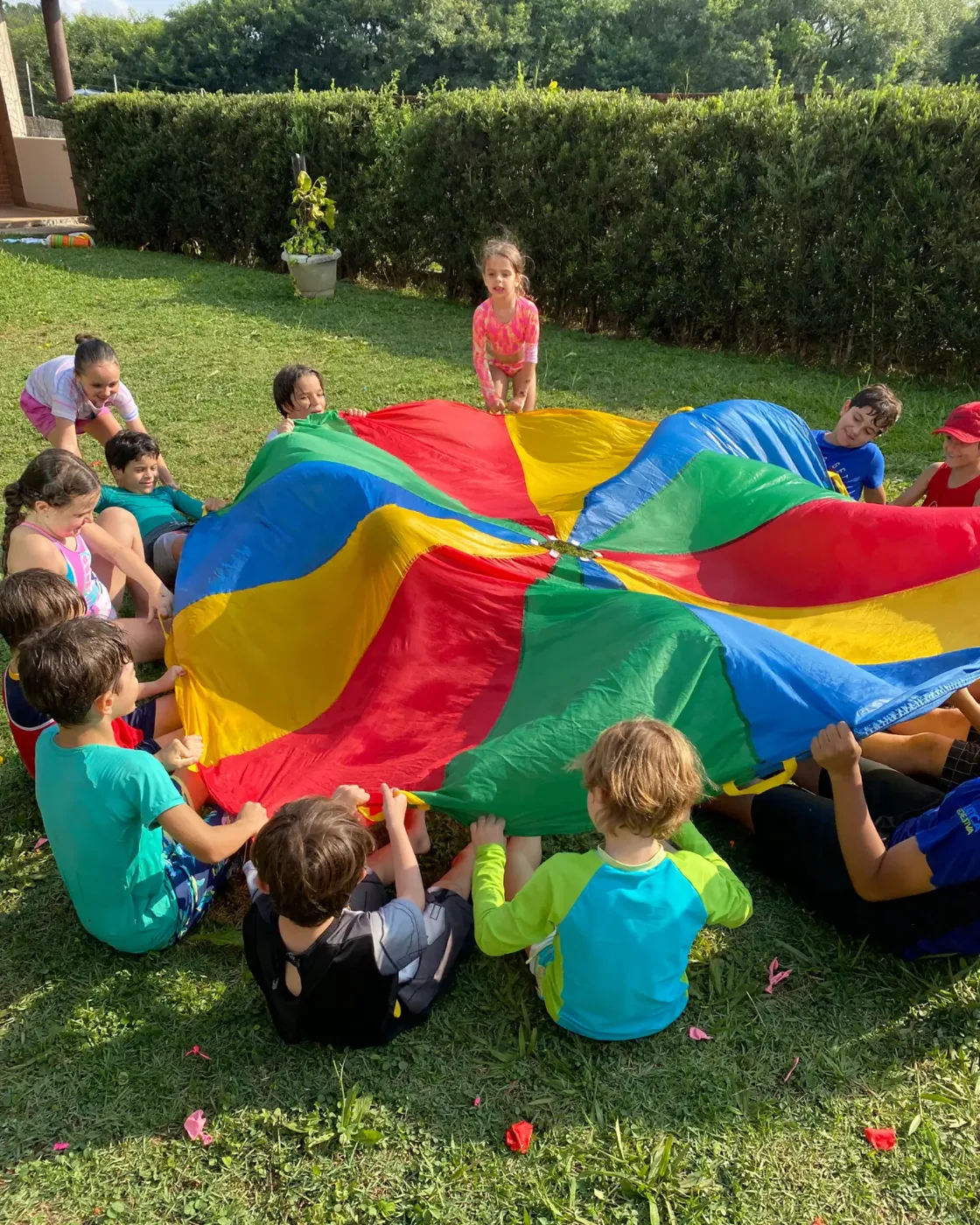 Crianças brincando com paraquedas colorido em festa infantil em São Paulo