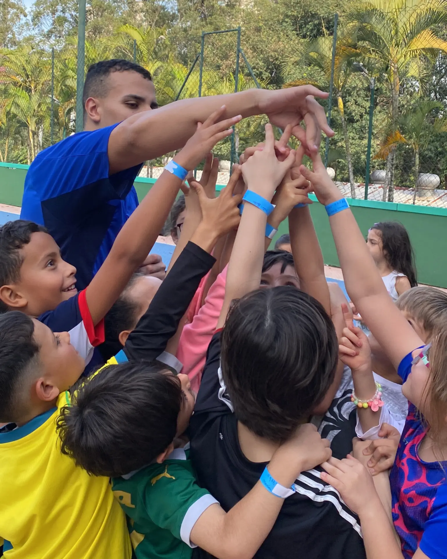 Crianças erguendo as mãos junto com o recreador ao final de uma atividade coletiva