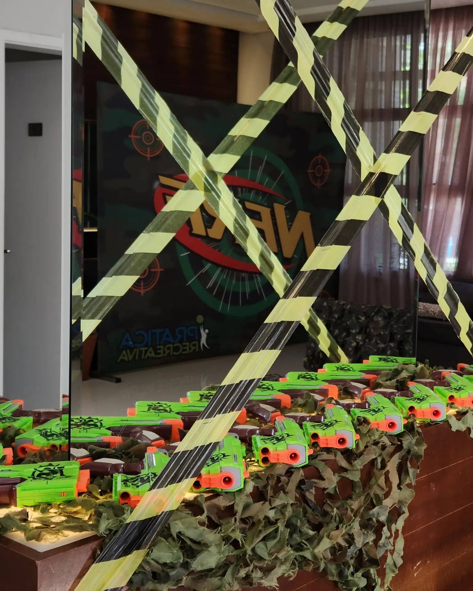 Lançadores Nerf organizados sobre a mesa decorada com camuflagem antes do início da festa