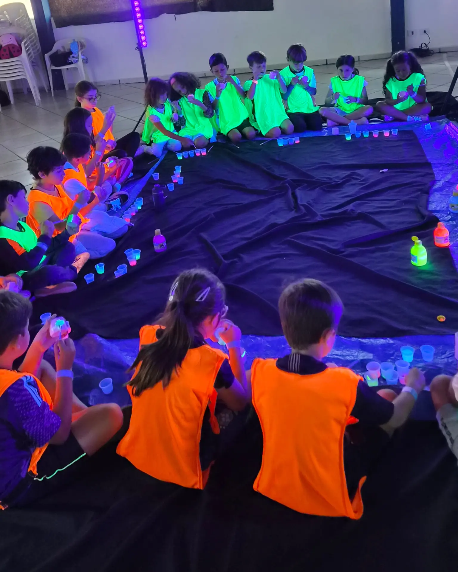 Oficina criativa com tinta neon para crianças em festa infantil à noite