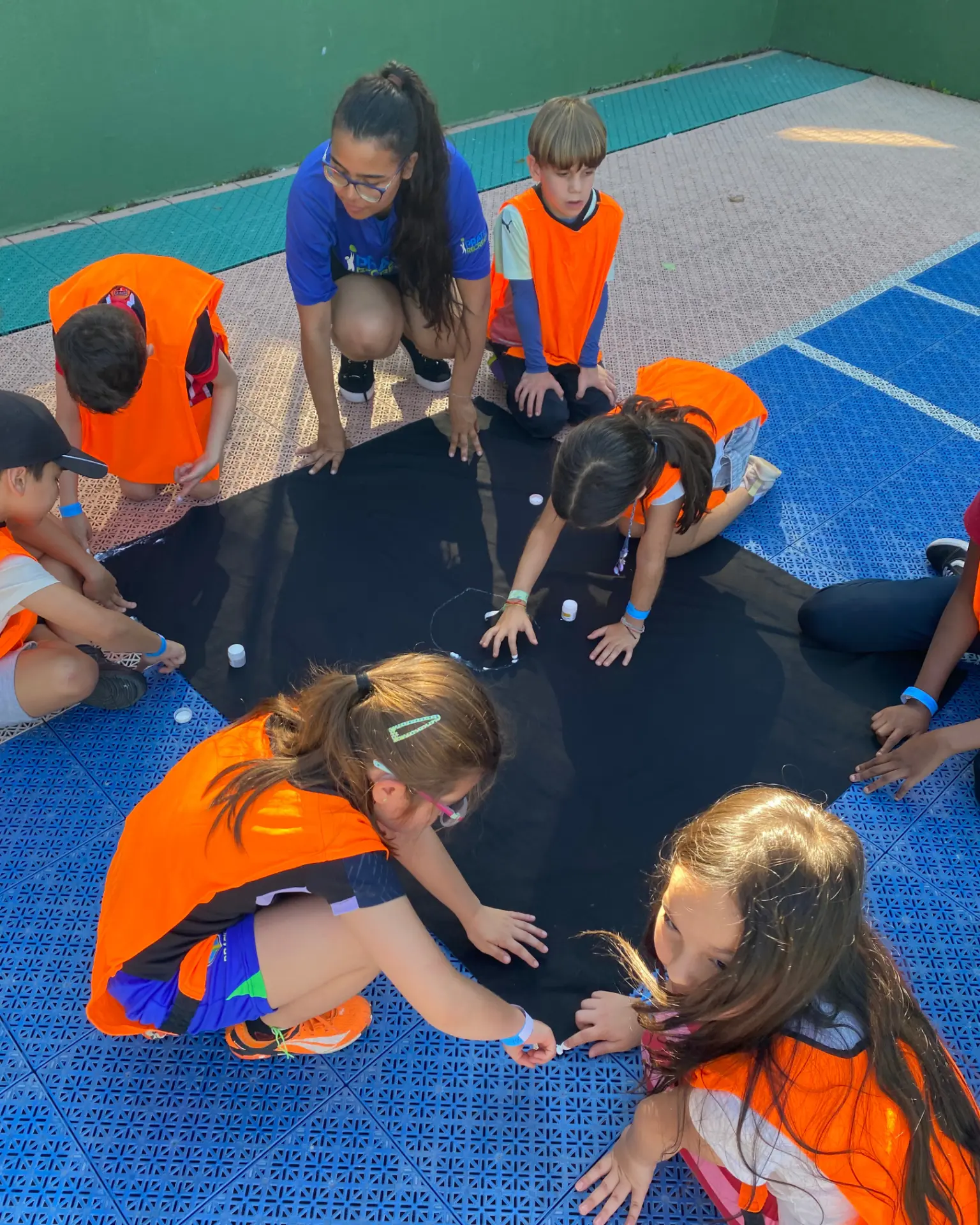 Recreadora e adolescentes em oficina criativa sobre tecido preto em festa Teen