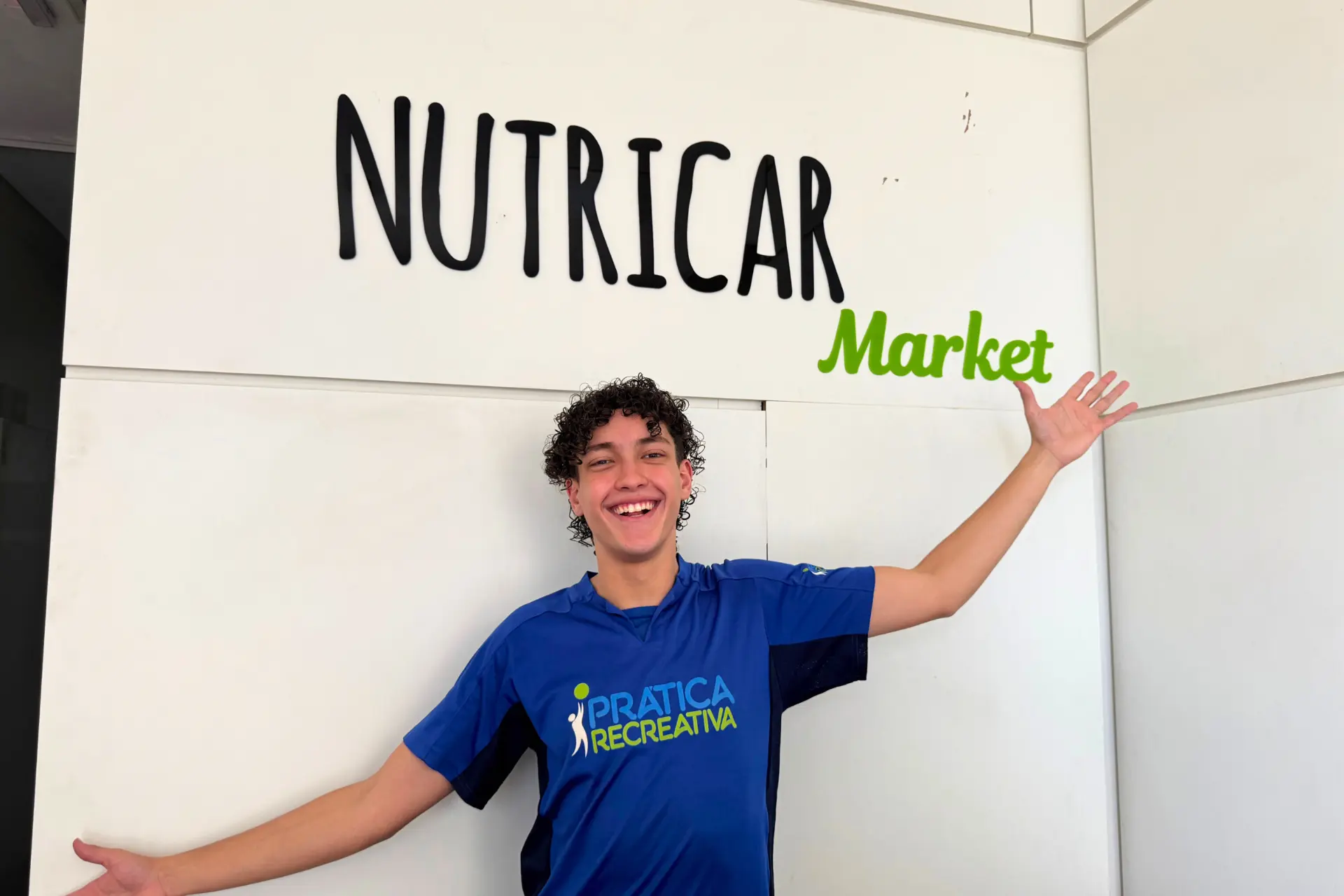 Recreador da Prática Recreativa em frente à identidade visual da Nutricar Market
