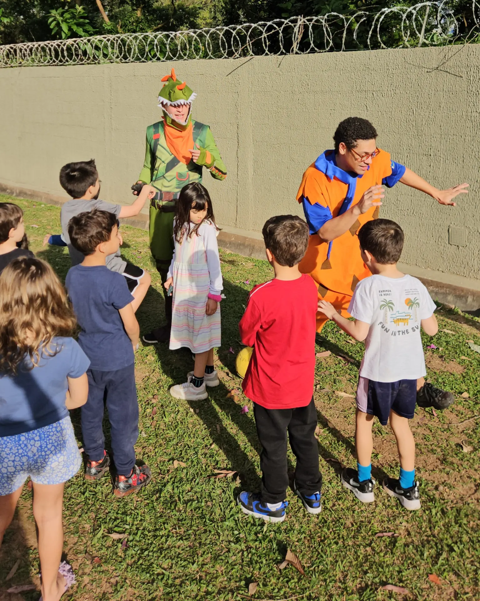 Dois recreadores fantasiados animando crianças no jardim durante festa de aniversário