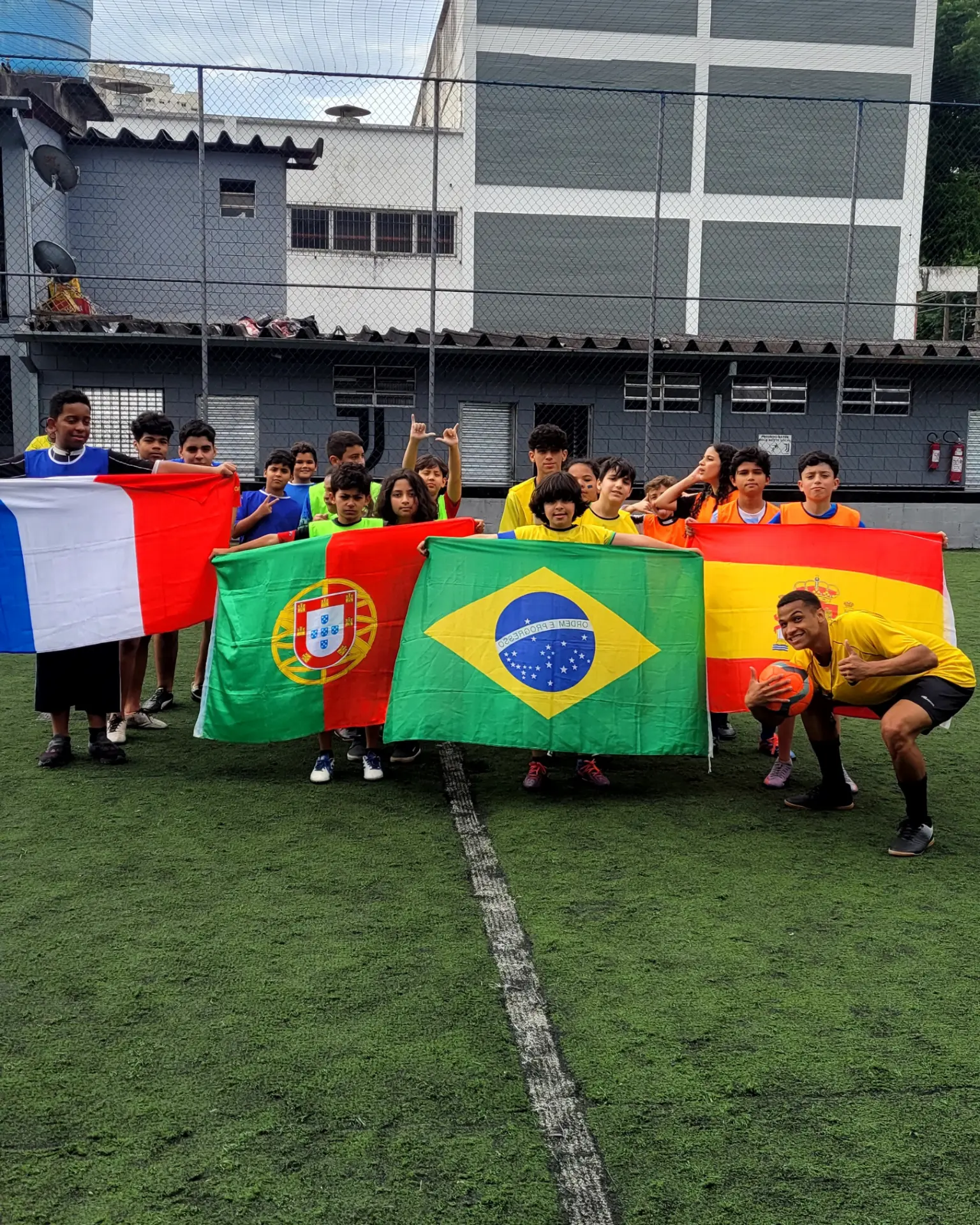 Crianças com bandeiras de países comemorando em campeonato de futebol estilo Copa do Mundo em festa infantil
