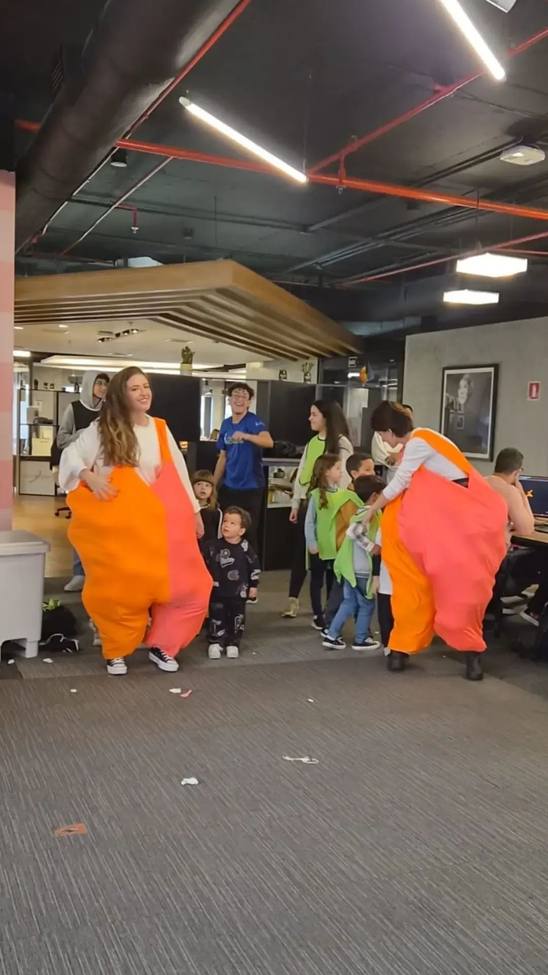 Recreadoras com fantasias infláveis animando crianças em evento de Dia das Crianças dentro de um escritório
