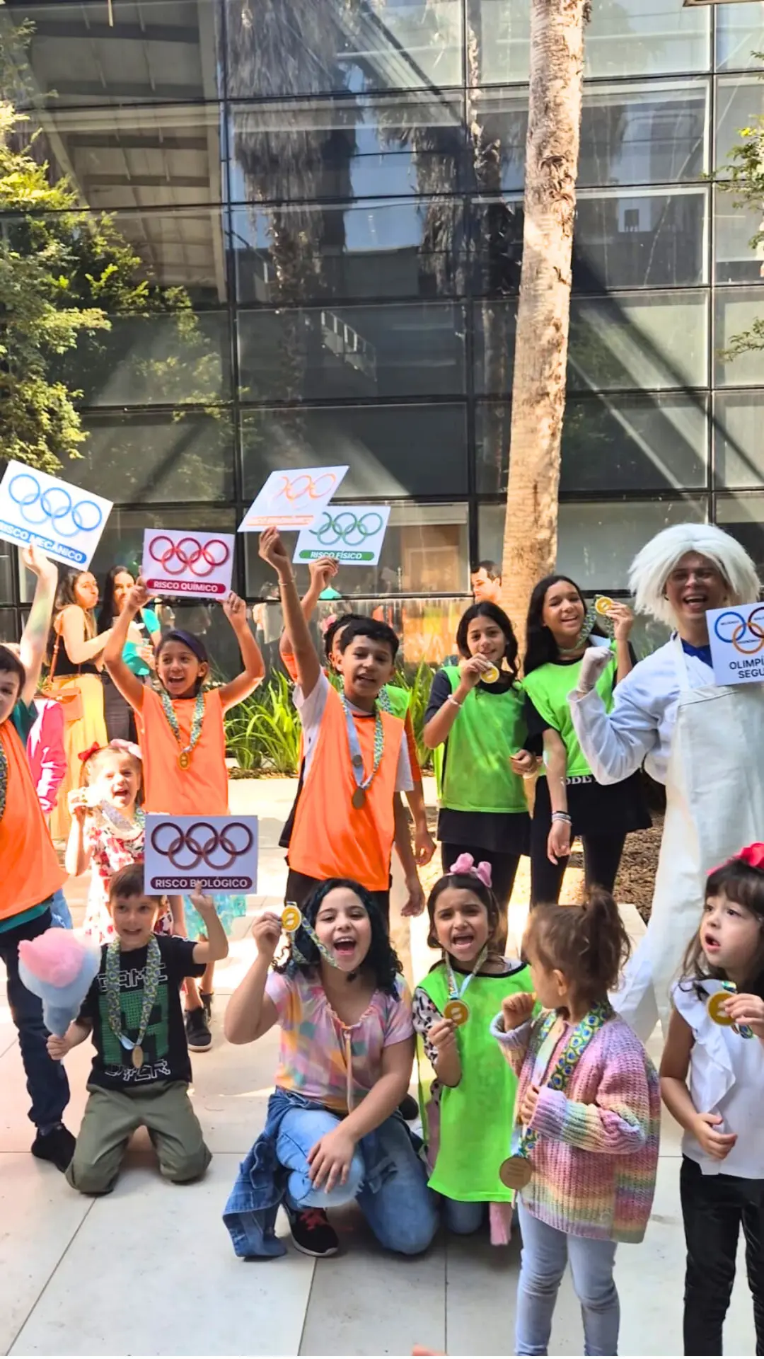Crianças comemorando com medalhas e placas nas Olimpíadas da Segurança em evento especial