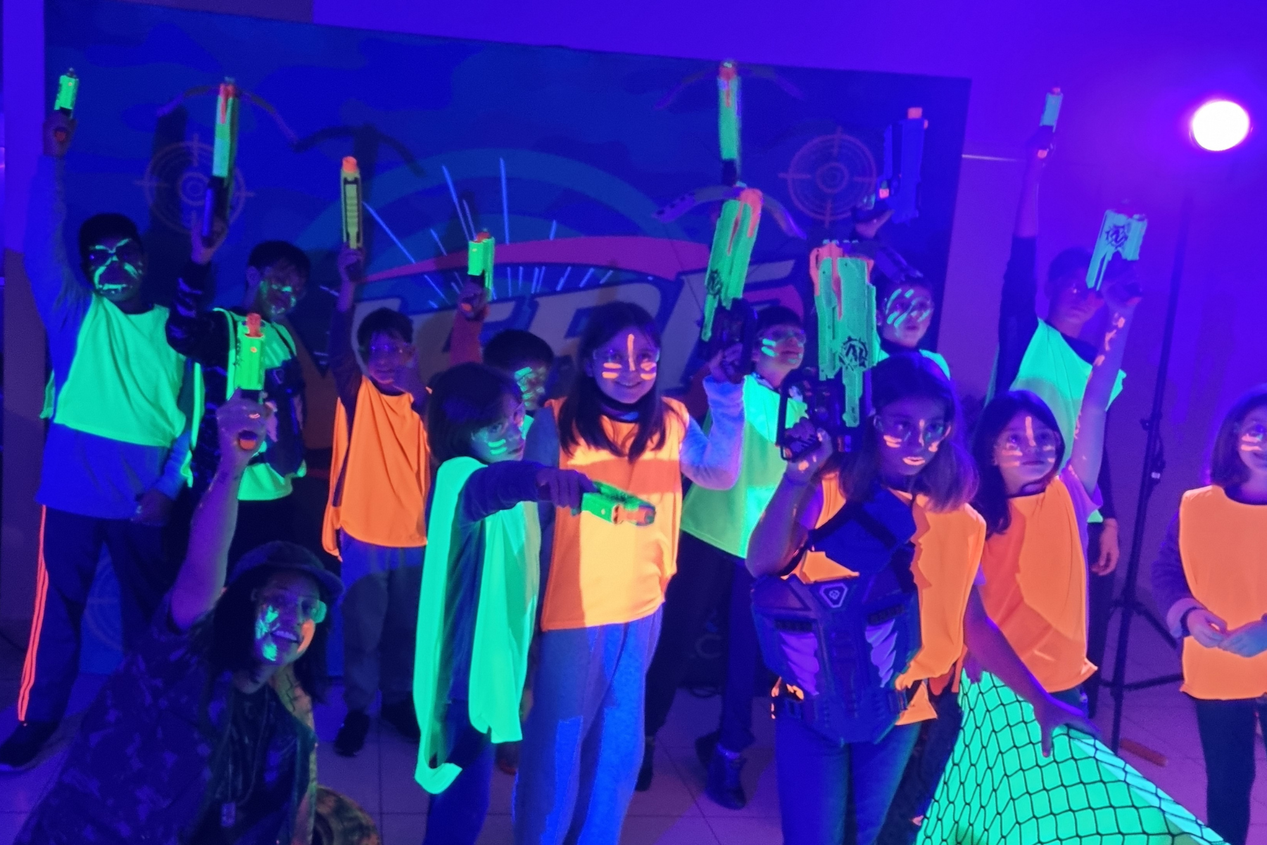 Crianças se divertindo na Arena Nerf com luz neon em festa de aniversário infantil
