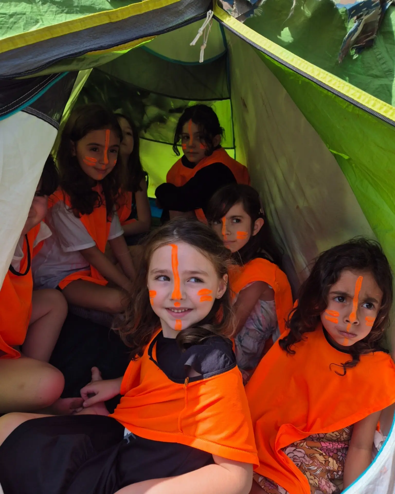 Meninas com pintura no rosto reunidas dentro da barraca de camuflagem em festa tema Nerf