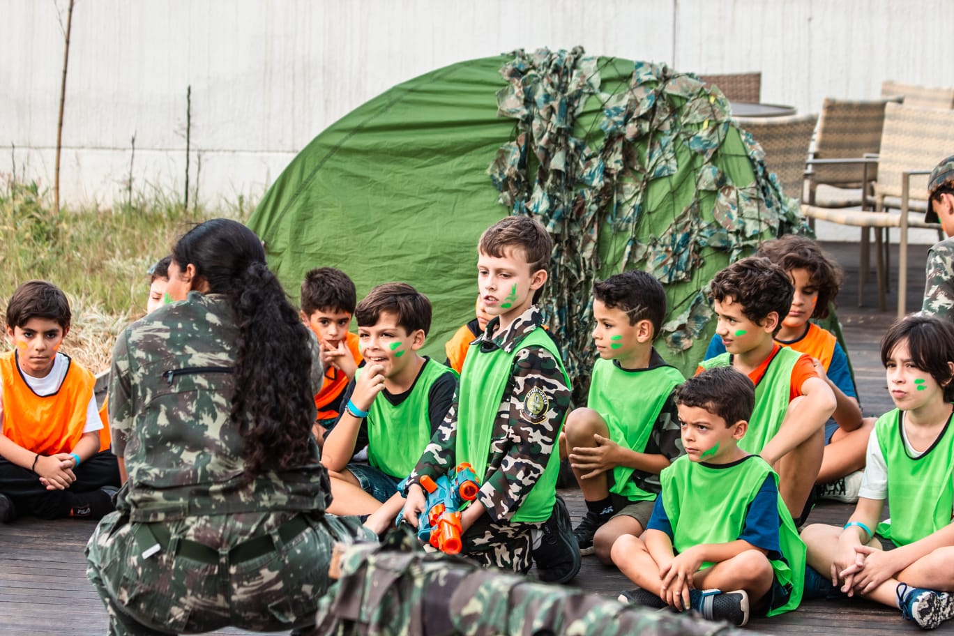 Recreador da Prática Recreativa explicando as regras para crianças sentadas antes da festa Nerf