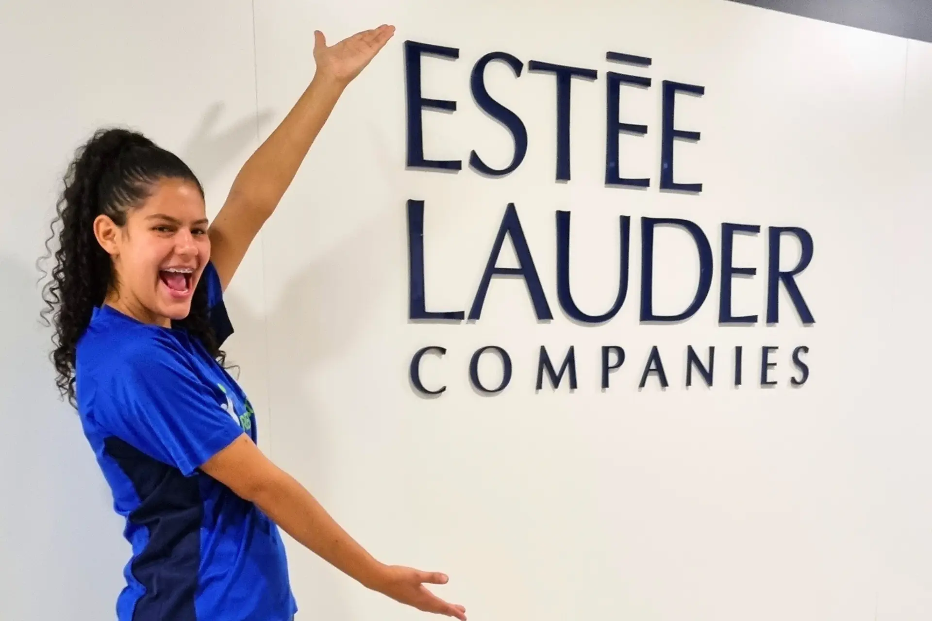 Recreadora da Prática Recreativa em frente ao letreiro da Estée Lauder Companies
